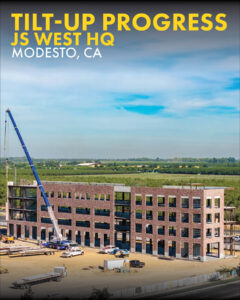 Drone photo of the construction of the JS WEST Headquarters project in Modesto, CA. You can see a large crane lifting concrete tilt up panels with a brick veneer as the facade for the structural steel frame.