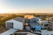 Aerial sunset view of the Lightfighter Village campus with the ocean and dunes in the distance